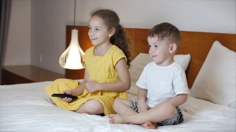 Portrait ute Little Kids While Watching TV on Laptop. Boy and Girl Watch Cartoon on Laptop on Living Room. Concept Video Game, Entertainment, Emotions, Family. Children Brother and Sister Watching TV