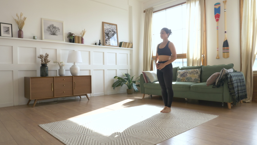 Woman in Leggings and T-shirt Doing Yoga Poses in Living Room on Sunny Morning Royalty-Free Stock Footage #1060523725
