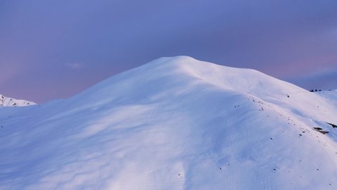 Aerial view of a winter mountain ridge before sunrise or after sunset. Snow covered top of mountain during sunset. Immaculate colored snow. slow motion: film stockowy