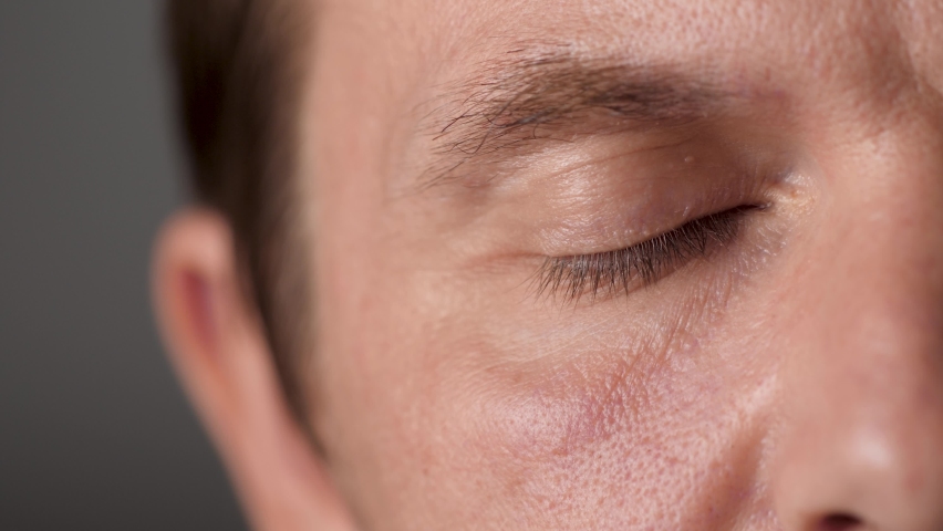 Man Half Face Opens Eyes and Looks Intently at the Viewer. Close-Up of Caucasian Man's Brown Eyes. Highly Detailed Portrait of Young Man Looking Into the Camera. Focused Man Gazing On Something. Royalty-Free Stock Footage #1060529002
