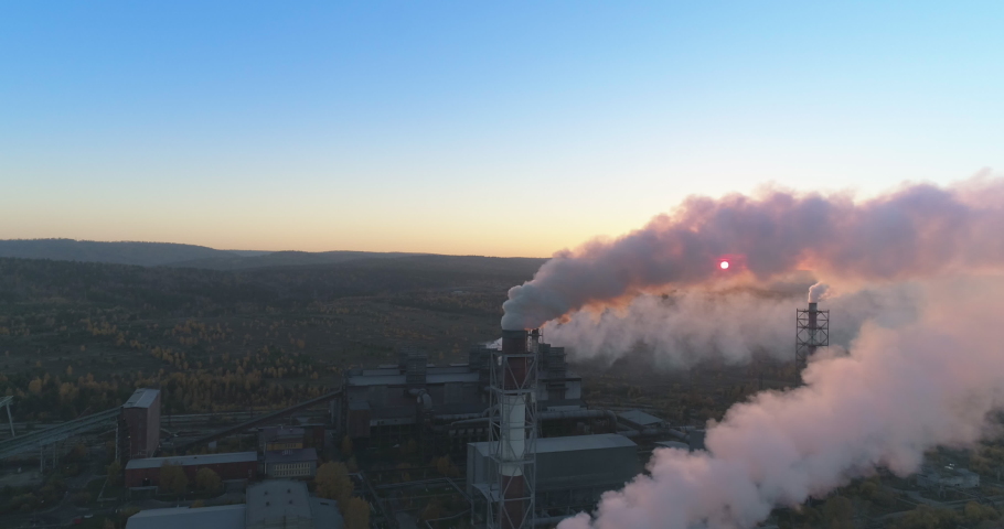 Aerial drone footage of steel factory pipes during sunset time. high above metallurgical plant and smoke cloud is coming from chimney. Aerial 4K Royalty-Free Stock Footage #1060529863