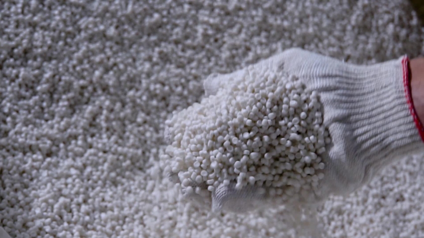 Plastic granules are poured from the hand in glow. Plastic granules, dye, polymer granules are used for the production of plastic products Royalty-Free Stock Footage #1060537165