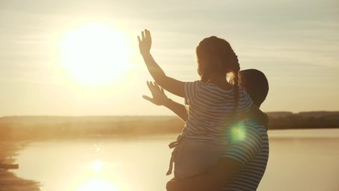 happy family dad and daughter by the sea at sunset silhouette. father and child kid reach out to the sun. kid dream concept. happy family little girl and dad alone with nature relax sunset concept