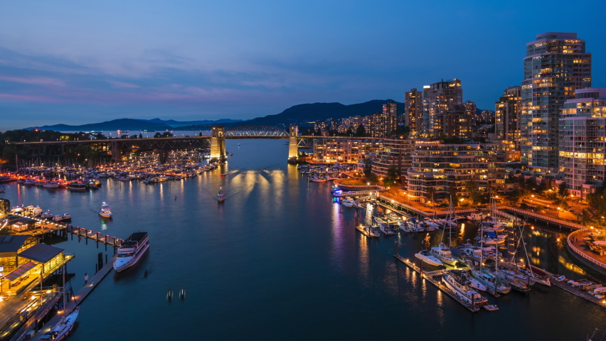 Vancouver, British Columbia, Canada, zoom out timelapse view of Downtown buildings and boats on False Creek at dusk. 