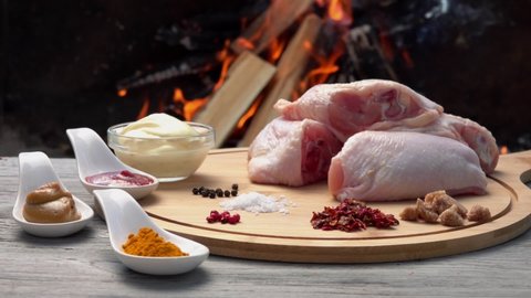 Raw chicken legs with spices on the background of the open fire. Ingredients for the preparation of delicious grilled chicken