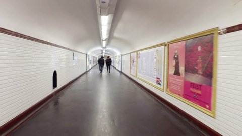 Paris, France - circa May, 2019: Personal perspective of tourist moving in underground metro station passage tunnels in Paris, France