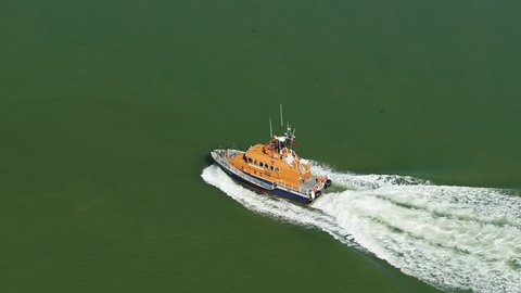 kemsley , kent / United Kingdom (UK) - 09 19 2019: Dramatic aerial tracking shot of a RNLI Lifeboat crew sailing along open water.