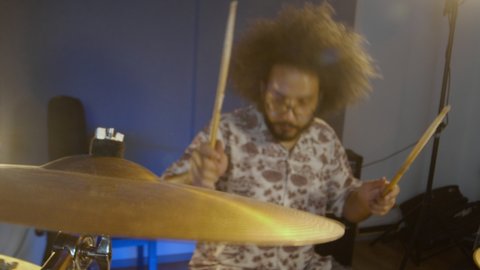 Drum player. Music recoding. Hispanic man playing drums in the rehearsal space. A brunette male person with afro hair learning new musical lessons.focus on the drum.