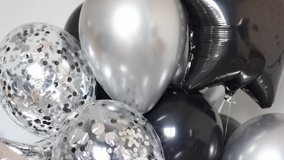 A bunch of black, silver and transparent balloons with confetti close-up.