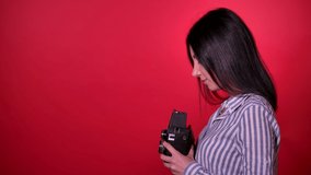A Fashion girl with a retro photo camera, Profile shoot isolated in red background