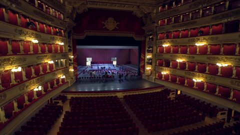 Milan, Italy, 14.10.2020: Teatro alla Scala. A view inside the building of an empty concert hall made of red velvet and an empty stage. Opera theatre. The workers set up a stage for the performances.