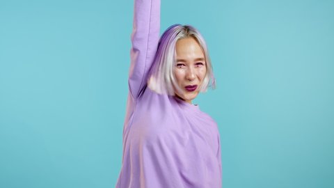 Woman with dyed violet hair very glad, she screaming loud. Woman trying to get attention. Concept of sales, profitable offer. Excited happy lady on blue studio background.