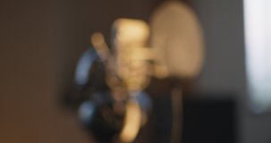 Music production. Blurred shot of microphone and headphones in sound record studio getting focused