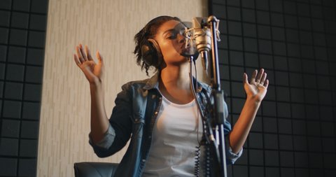 Music star. Emotional black female singer recording song at professional sound record studio, slow motion