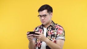 Handsome man playing game on smartphone using modern technology - apps, social networks isolated on yellow background.
