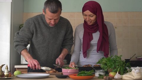 An authentic adult Arab Muslim married couple, a man and a woman in a hijab have fun cooking dinner together. Halal food, religion and traditions, Muslim holiday