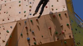 strong male rock climber on vertical artificial rock wall on outside climbing gym, extreme sports, strength, training rockclimbing. High quality 4k footage