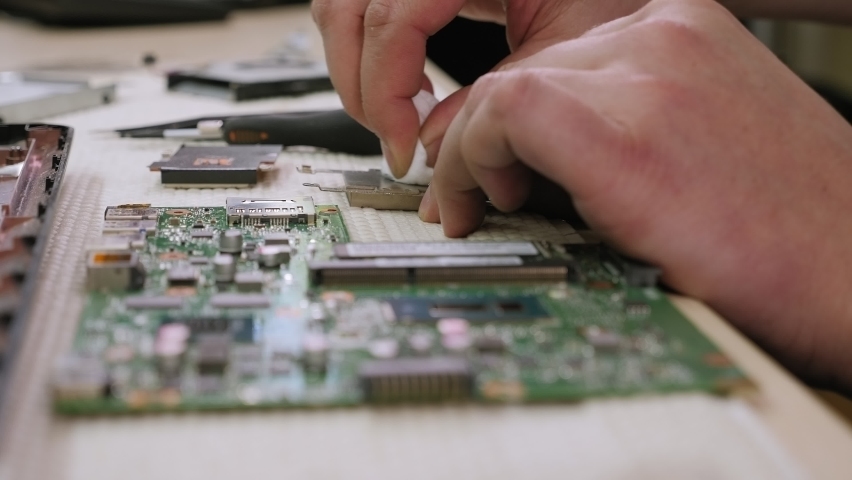 Repairman cleans laptop processor from old thermal paste. Service electronics and computers concept. Royalty-Free Stock Footage #1060579327