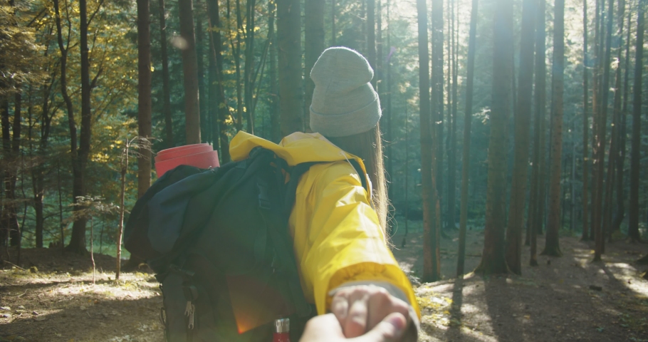 First person view. Happy woman with backpack walking in forest and holding man hand. Close up of beautiful joyful female traveler smiling and trekking outdoors. Tourism concept. Vacation adventure Royalty-Free Stock Footage #1060583944