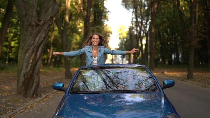 Two women friends having fun while driving convertible car on the street