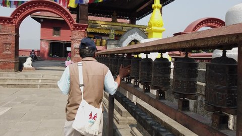 Kathmandu , West / Nepal - 05 28 2019: Nepalese guide spins prayer wheels on tour of Swayambhunath in Nepal