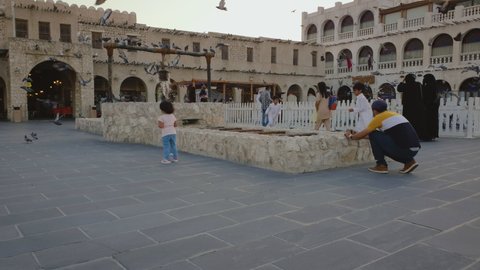 Doha, Qatar- October 10 2020: Souq Waqif at sunset showing Old Well Fountain  with pigeons flying, visitors walking and talking pictures 