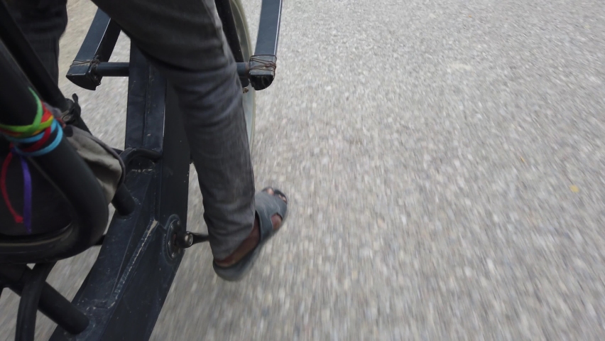 Bicycle taxi driver in jeans and sandals pedals passenger in Nepal