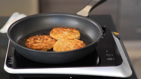 Close-up of frying chicken burger patties on a hotplate. A hotplate is a portable burner popular for college dorms.