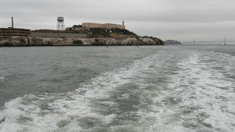 Alcatraz island in San Francisco Bay, California USA. Federal prison for gangsters on rock, foggy weather. Historic jail, cliff in misty cloudy harbor. Gaol for punishment and imprisonment for crime.