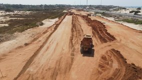 Aerial view of heavy machinery, Articulated truck moving dirt on a new road construction site, heavy equipment top down footage of dump truck
