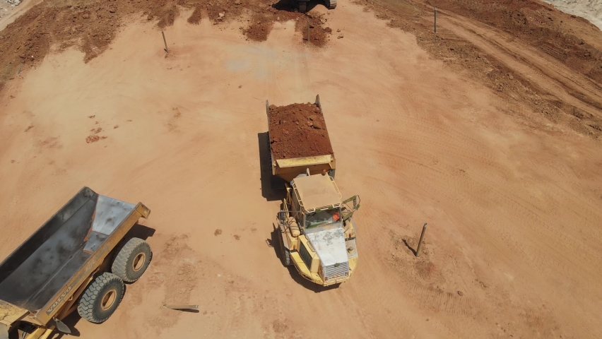 Aerial view of heavy machinery, Articulated truck moving dirt on a new road construction site, heavy equipment top down footage of dump truck
