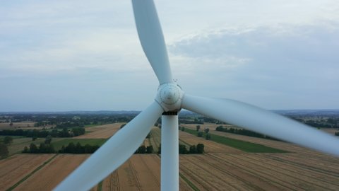 
Drone close-up shot of a wind turbine generating renewable energy from the wind. Aerial view. Wind turbines rotate slowly in a beautiful field at sunset.