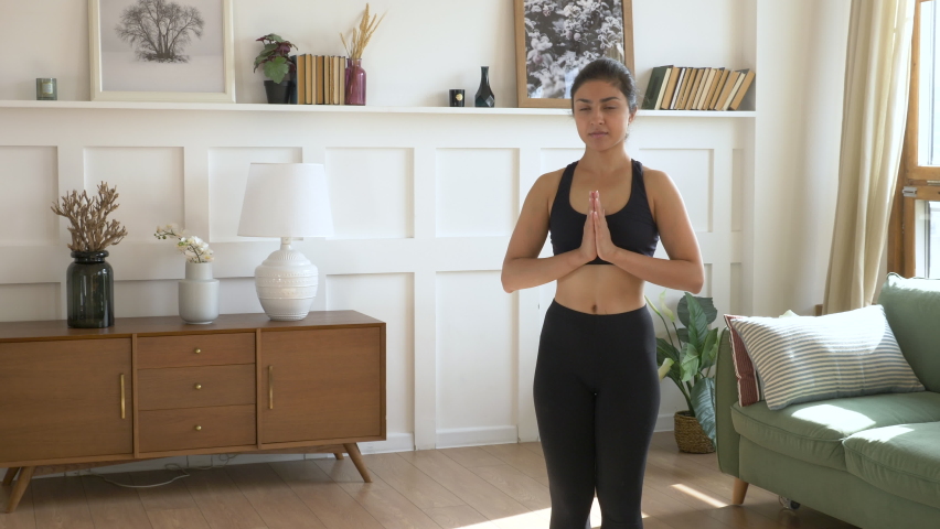 A young Indian Woman Meditates in the Morning, She Does exercises for Balance And Stretching does sports Yoga, Black Sportswear Leggings and a Top, a Bright Room At Home Royalty-Free Stock Footage #1060592530