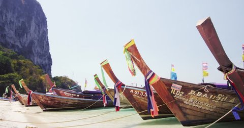 KRABI, THAILAND - MAR 3, 2015: Thai tourist boats decorated with colorful strips on sandy beach of tropical resort waiting for travelers to take a tour trip around the island