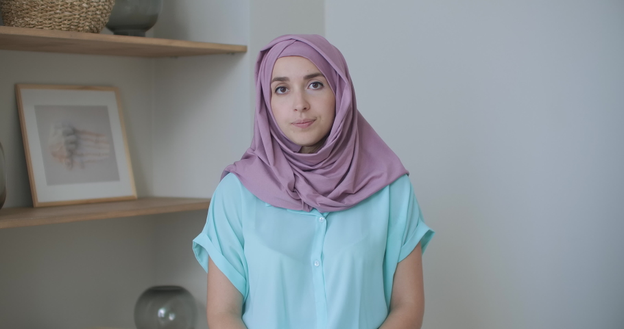 A woman in a hijab looks into the camera and silently nods her head and listens. Conversation via video link. Video conference listen to the doctor's recommendations. 