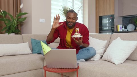 African american man celebrates birthday during quarantine blowing candles on webcam talking with family members communicating online. Birthday at home. One person. Self-isolation.