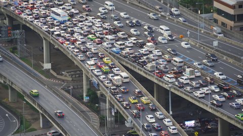 Aerial view of busy cars with traffic jam in the rush hour on highway road street on bridge in Bangkok Downtown, urban city in Asia, Thailand at sunset. Intersection junction. Toll gate in Rama 9