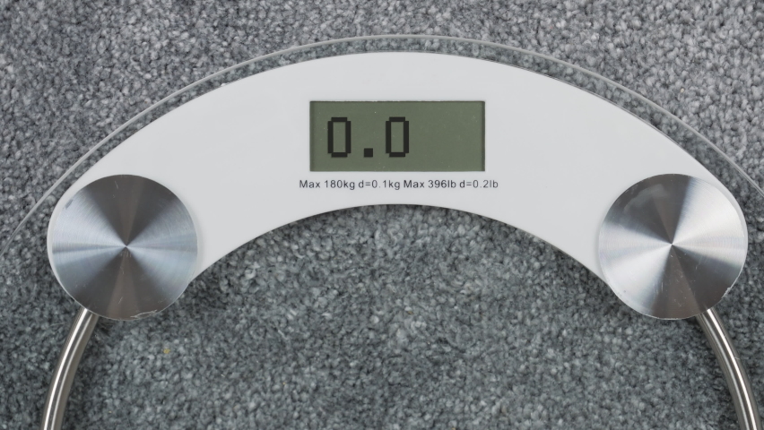 Diet. A person steps on the digital scales to check her weight. Inscription Help on a digital display, conceptual footage. First-person view from above Royalty-Free Stock Footage #1060599712