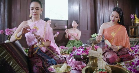A beautiful asian female dress on Ayutthaya cultural fashion clothes sitting and flower decuration training traditional Thailand tomyam in the vintage old style ancient house