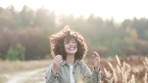 young pretty mixed race teen girl outdoor in sunlight. happy child of generation z laughs and adjusts her finely curly hair.