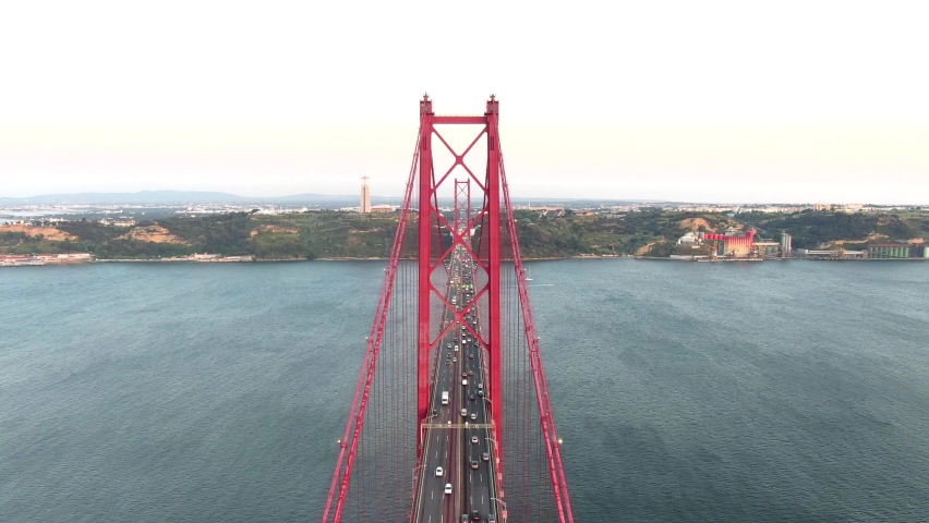 Aerial drone zoom view of Lisbon Ponte 25 de Abril suspension bridge cars driving at sunset, Portugal Royalty-Free Stock Footage #1060605088