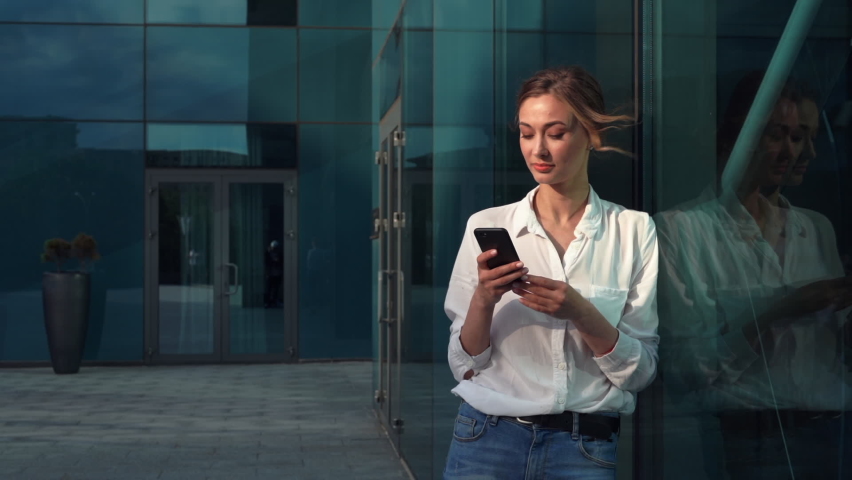 Businesswoman successful woman business person standing outdoor corporate building exterior cell phone Pensive elegance cute caucasian professional business woman middle age dreaming with mobile phone | Shutterstock HD Video #1060605925