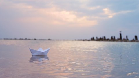 A paper boat floats on the sea against the blue sky. The concept of teamwork, business development and support.