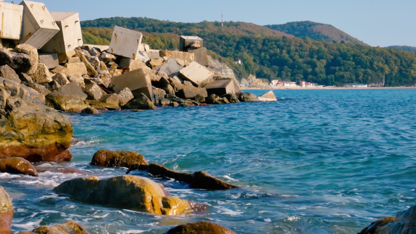 Sunny rocky seashore filled with concrete cubes of breakwaters.