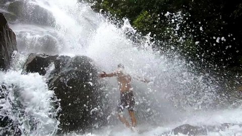 man bathing in the waterfall and enjoying in nature at morning clip is showing the people love towards nature.