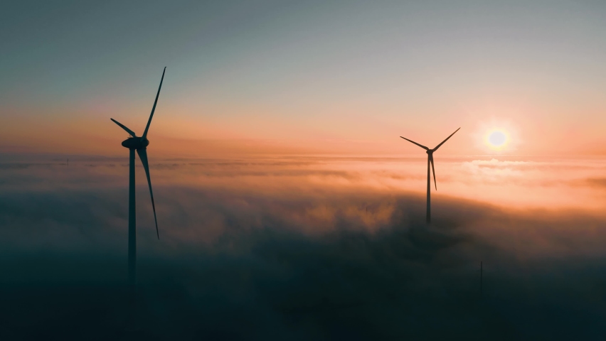 Wind turbines at sunrise in heavy fog. Wind farm generating green energy | Shutterstock HD Video #1060610542