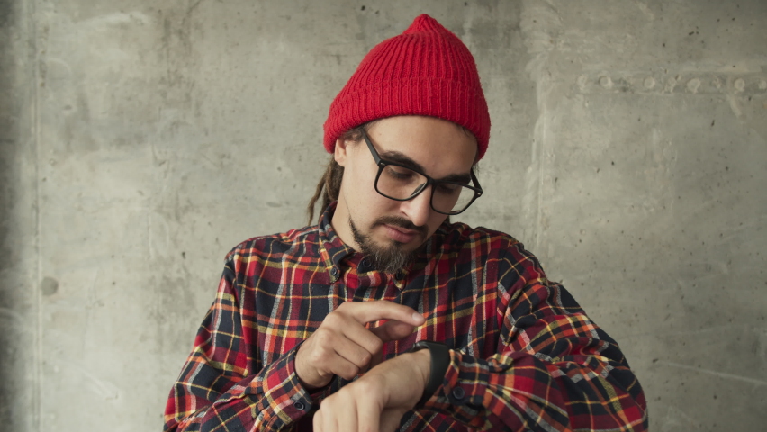 Attractive man using his smartwatch and controlling his smart home, hipster freelancer use smart watch