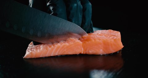 Sushi Chef cutting piece of salmon with silver knive 4K