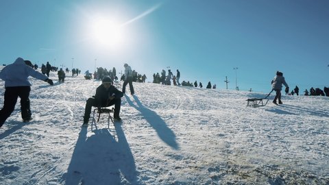 Bansko, Bulgaria - circa Jan, 2020: Healthy kids sledding on a winter day with tourist people enjoying sunny weather
