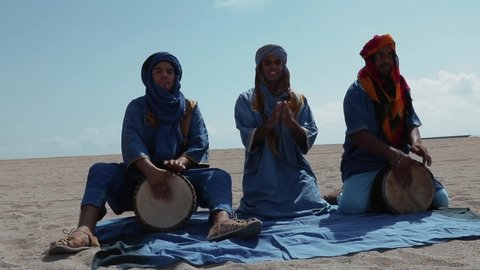 Morocco. 10-14-24: Men in traditional Tuareg blue dresses, playing ethnic percussion in the Sahara desert in Morocco.